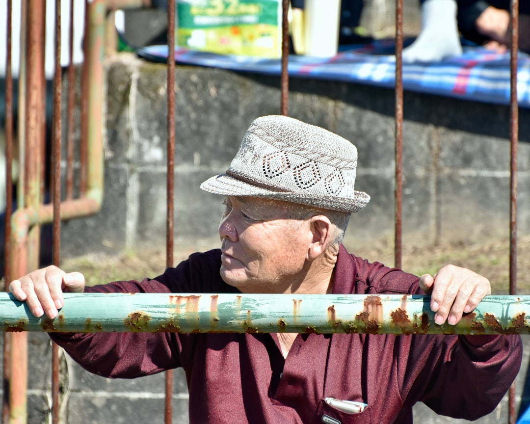 A man in a hat leaning on a fence