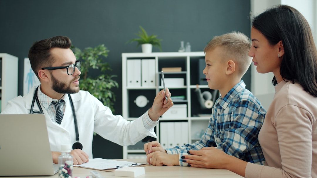 Doctor examines a young boy with his mother present.